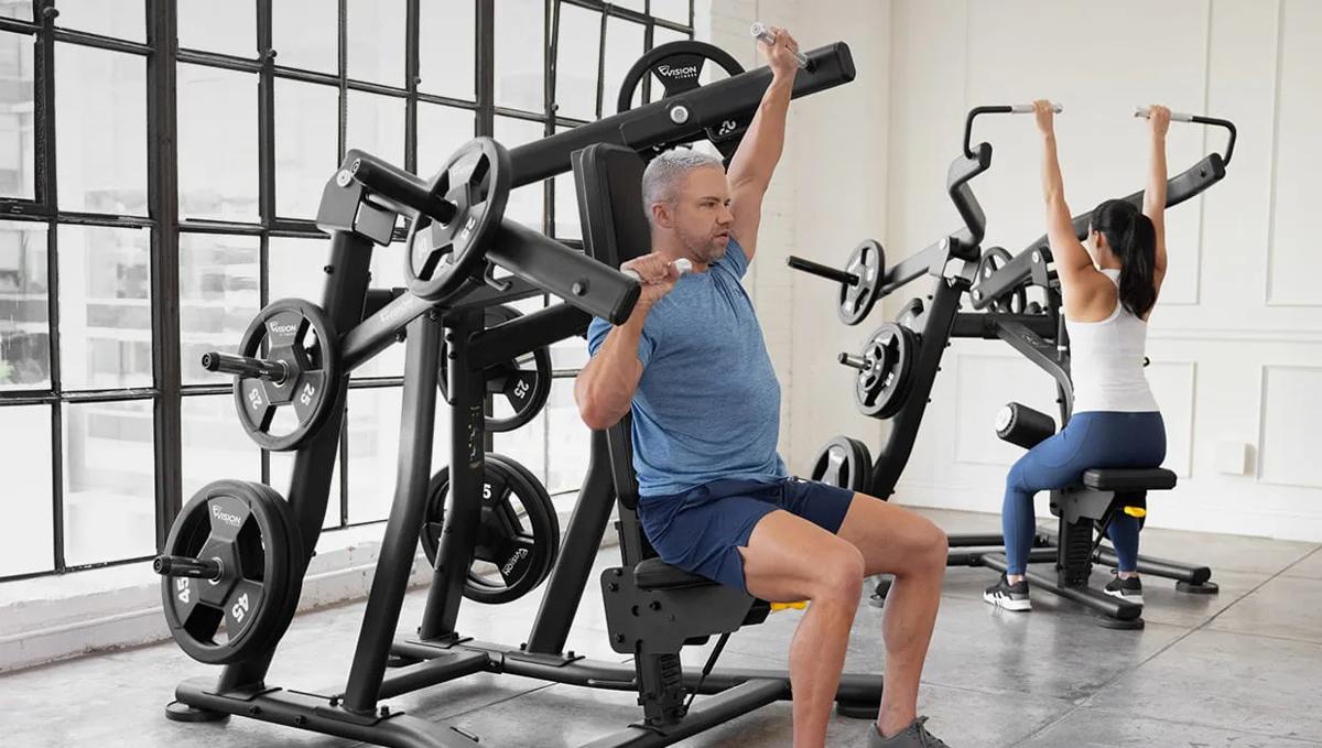 Two people using Vision Fitness plate-loaded shoulder press machines