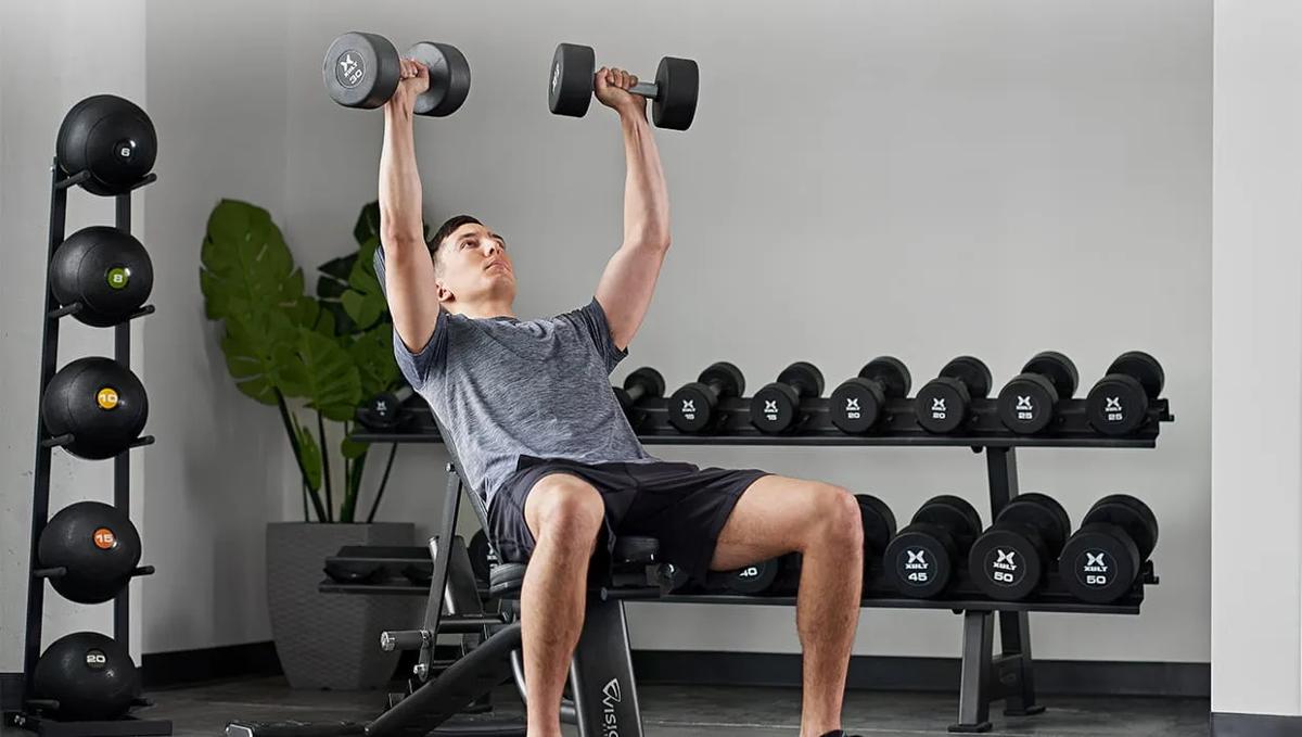 Person using a Vision Fitness adjustable bench with dumbbells